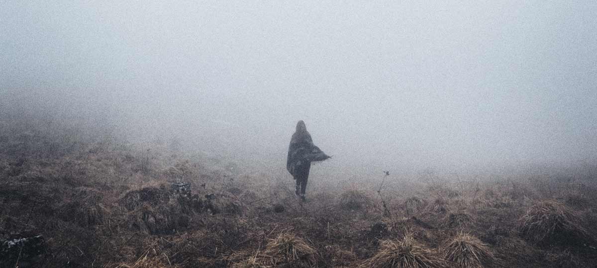 Harvested field, woman walking into thick fog