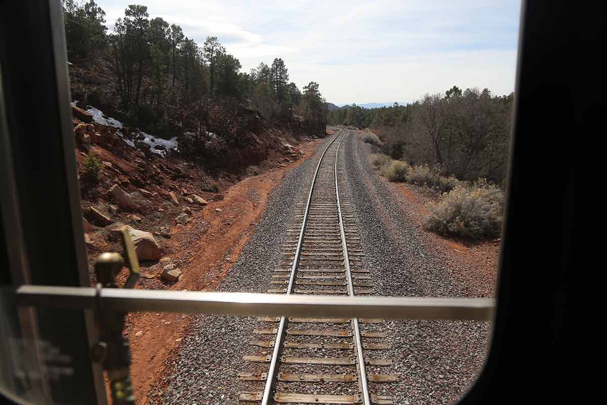 Looking back from the train at single train track weaving around a curve in the mountains