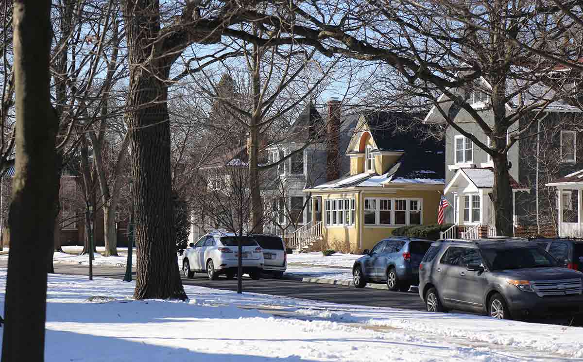 Residential street with cars, houses and trees and snow