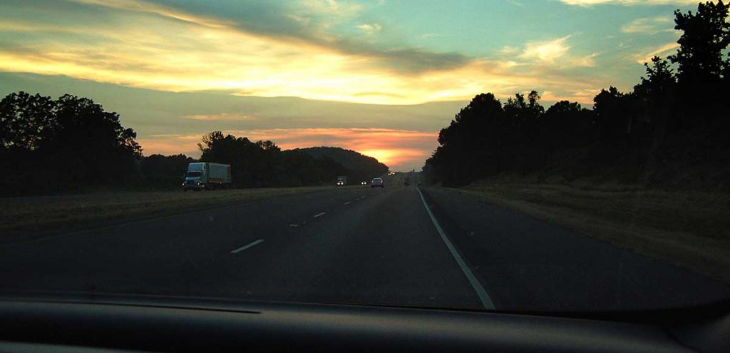 Road at dusk stretching into sunset