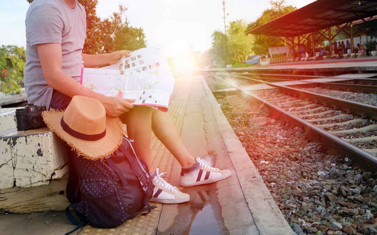 Girl sitting with her pack on a train platform looking at a map