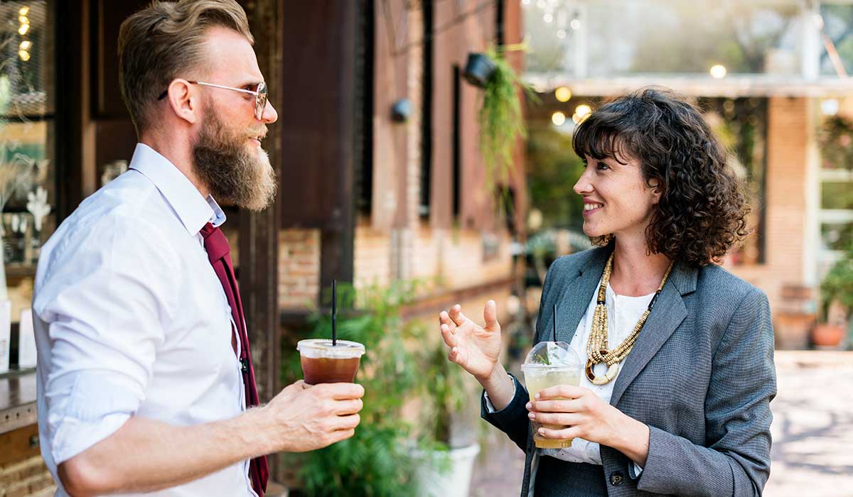 Standing man and woman engaged in active conversation that includes listening to each other