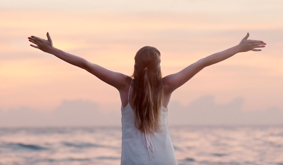 woman stretching out her hands in embrace of accomplishment