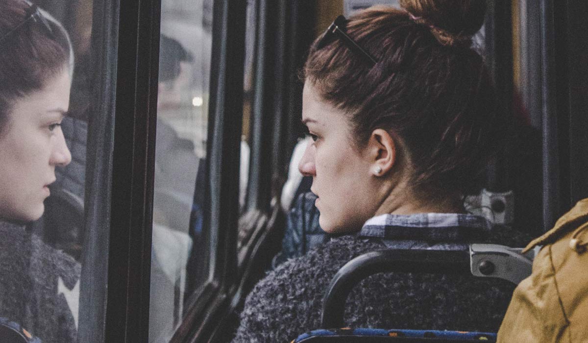 woman  on tram looking out the window, seeing her reflection