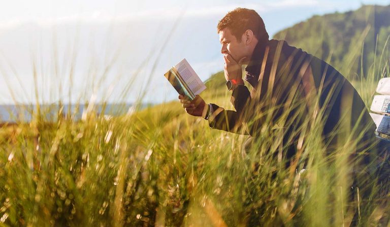 Man on a bench reading a book in seaside landscape