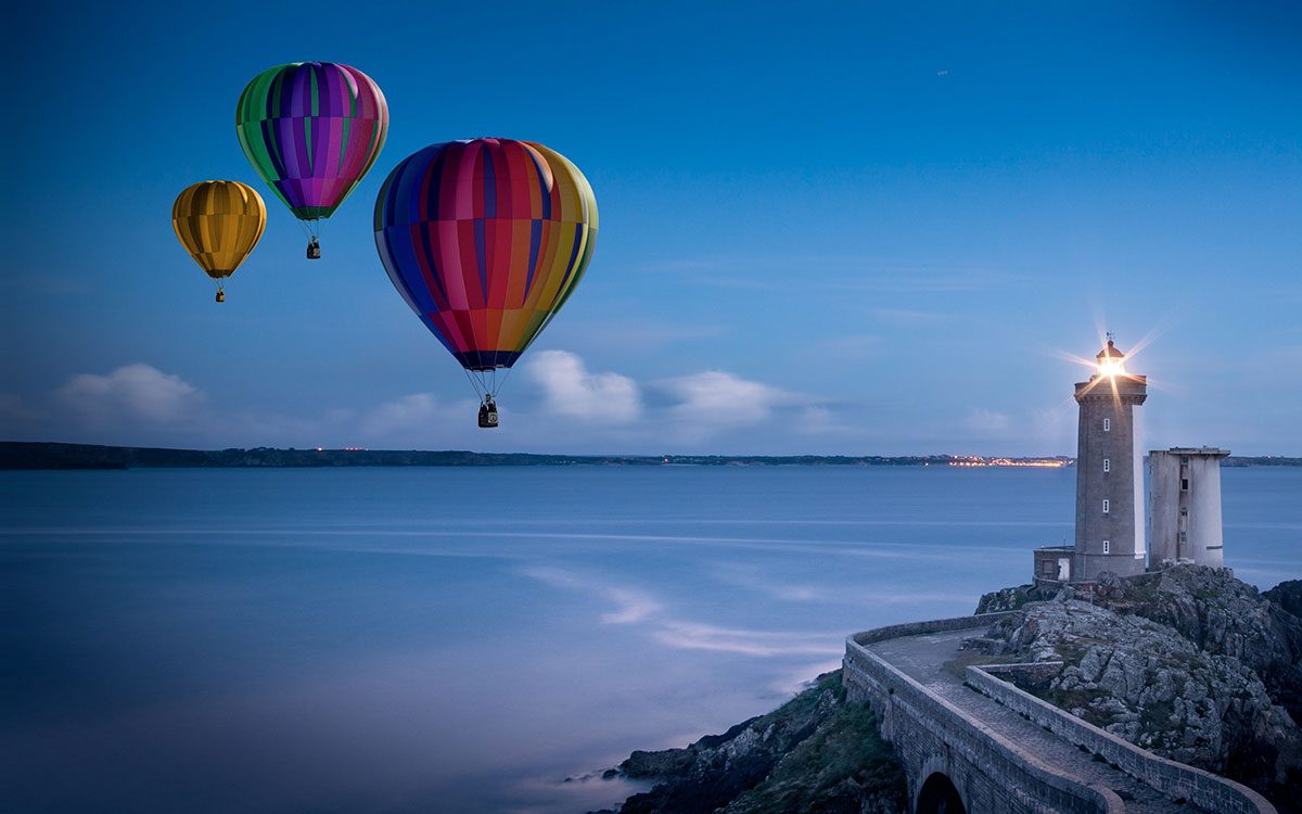 3 balloons over sea, lighthouse in foreground