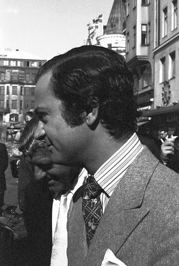 King Carl XVI Gustav on sidewalk with a small crowd surrounding him