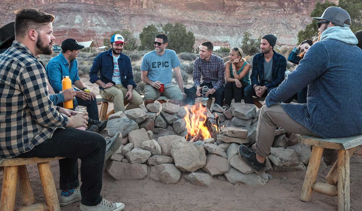 Group of men and women around campfire talking