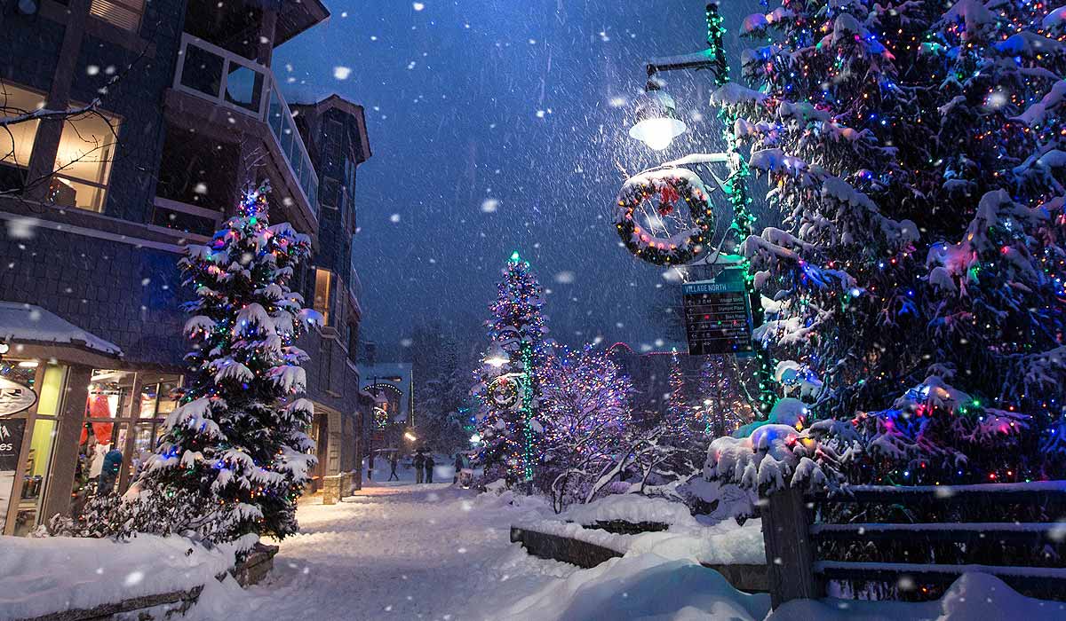 Street in village at Christmas - lights, decorations, snow on ground and falling