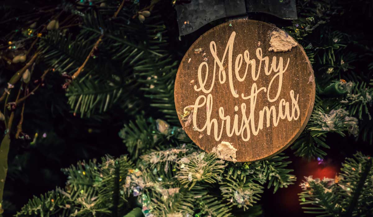 Christmas tree with wood ornament that has "Merry Christmas" written on it