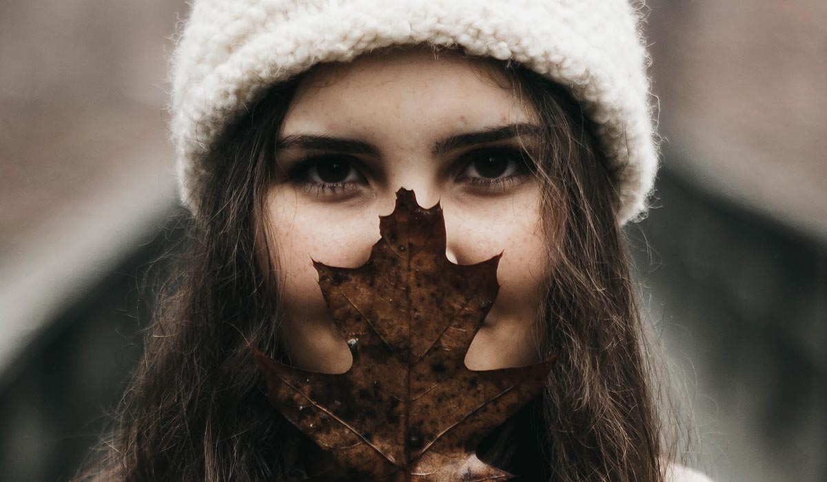 Woman, much of face hidden behind big leaf