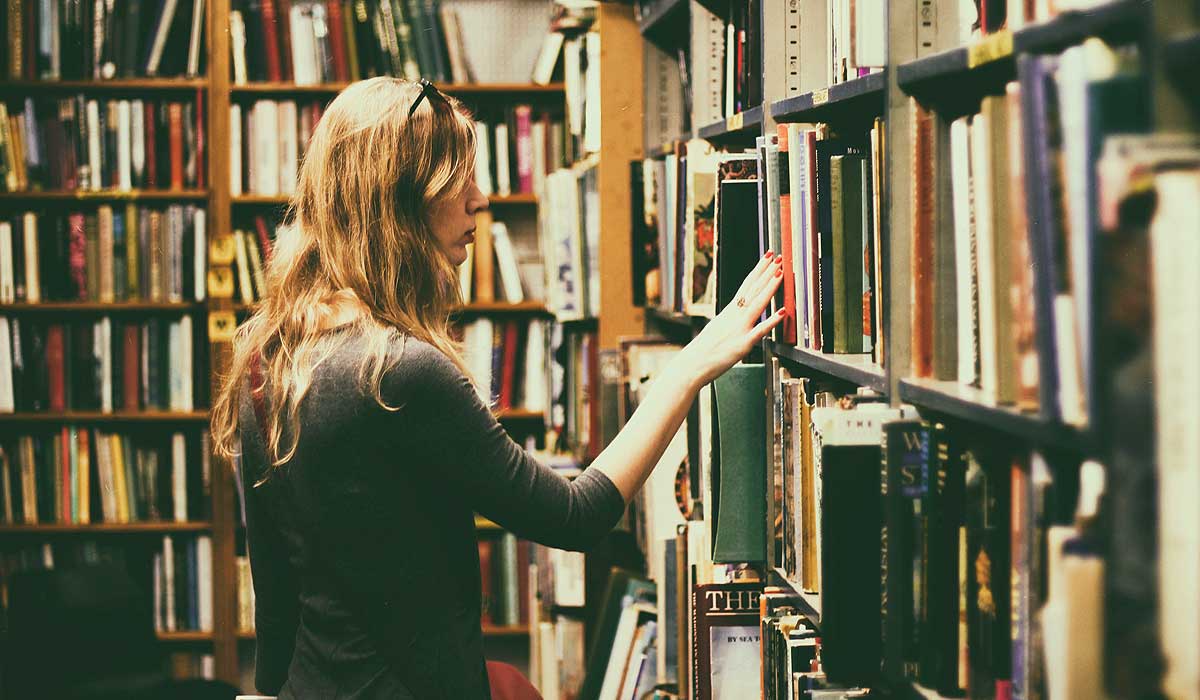 Woman perusing book shelves in library