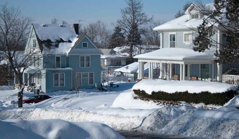 Picture perfect snow in Council Bluffs, Iowa. Old houses on a hill covered by and surrounded by deep snow. Sunshine and blue sky.