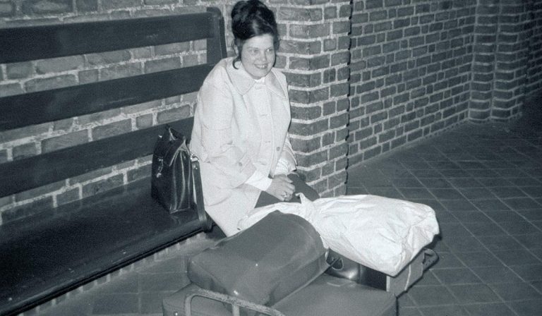 woman on bench at train station with lots of luggage