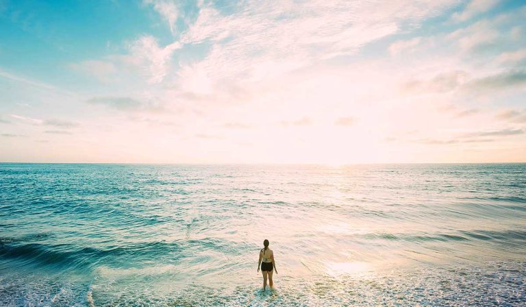 woman at waters edge, looking out over sea to horizon, asking what if