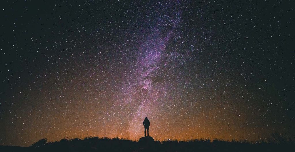 night sky: person silhouetted against stars and Milky Way