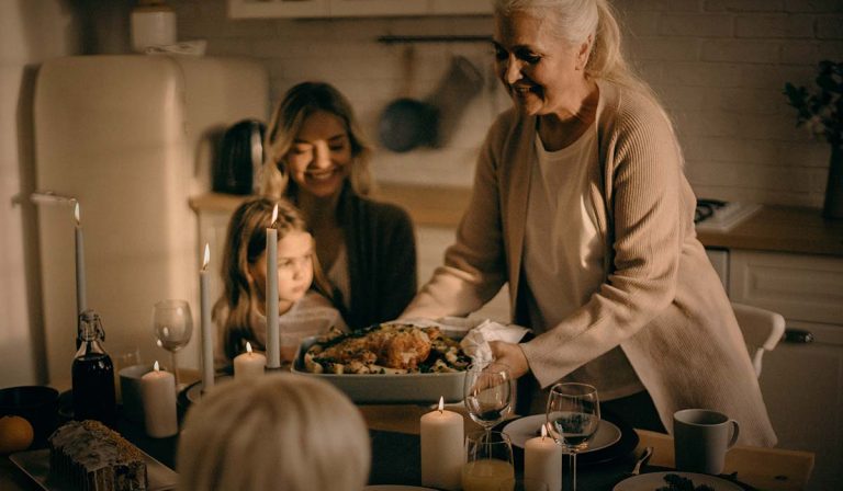 Woman brings pan with meat to dinner table