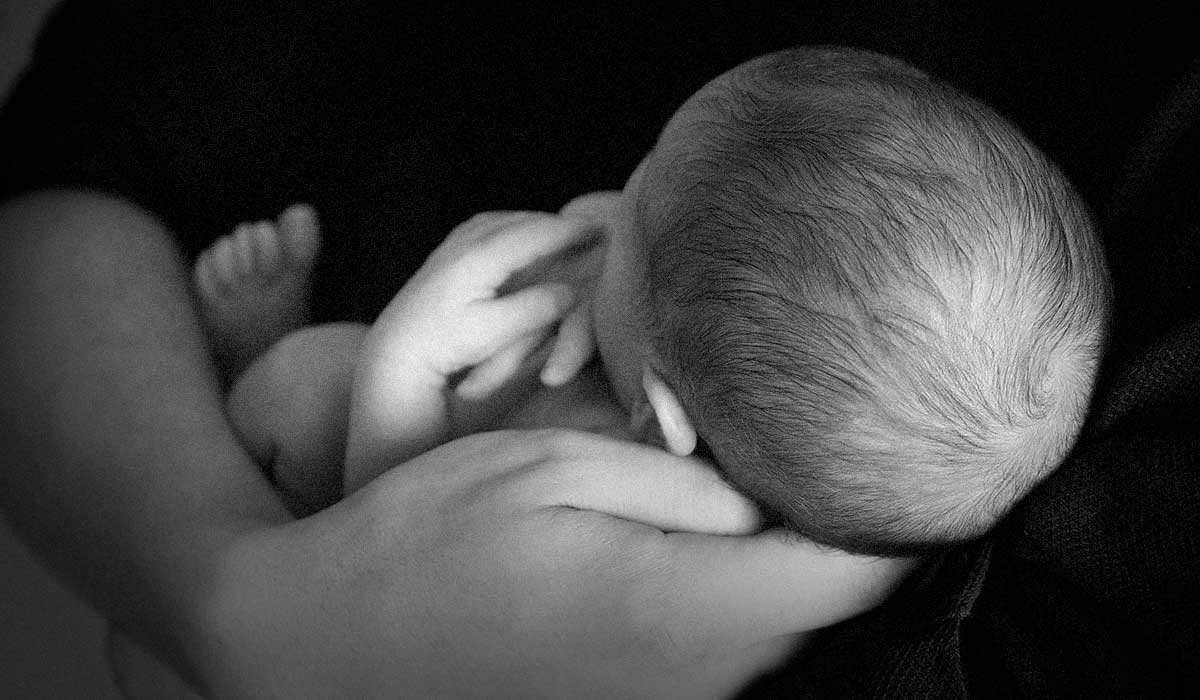 tiny baby held in adult's arms