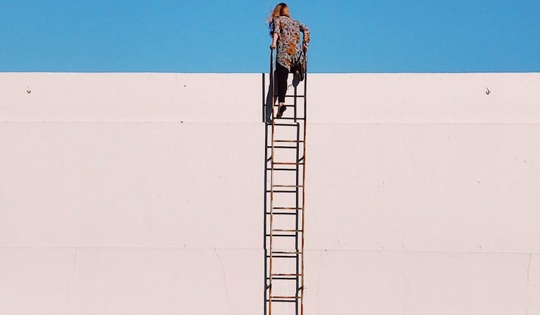 woman climbing a ladder to top of wall