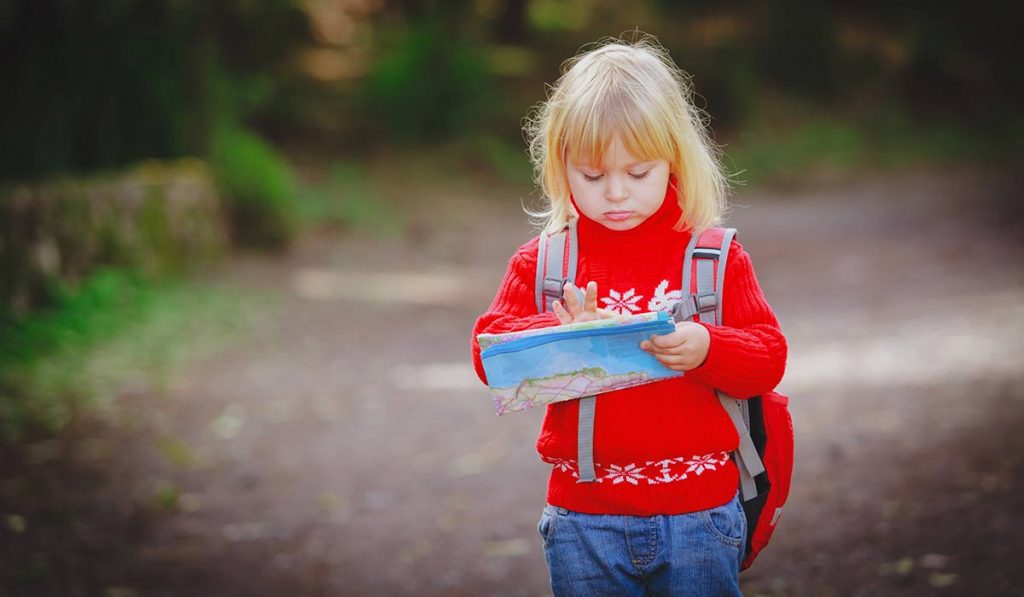 small girl with backpack checking her map