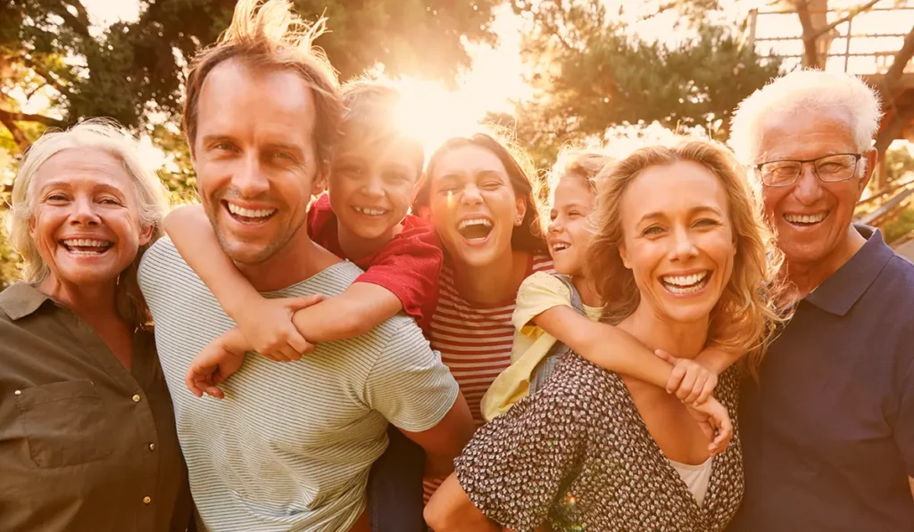 group of happy people, old and young, with sun rising behind them