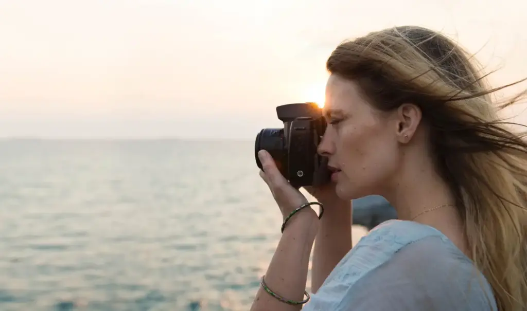 Woman pointing camera out over sea to take picture