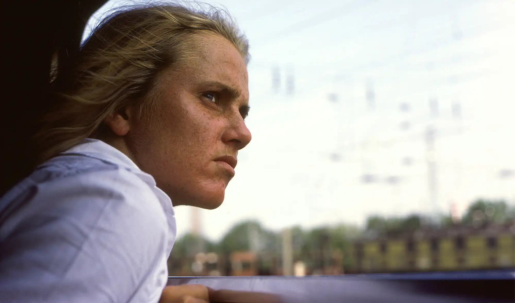 Young woman looking out open train window