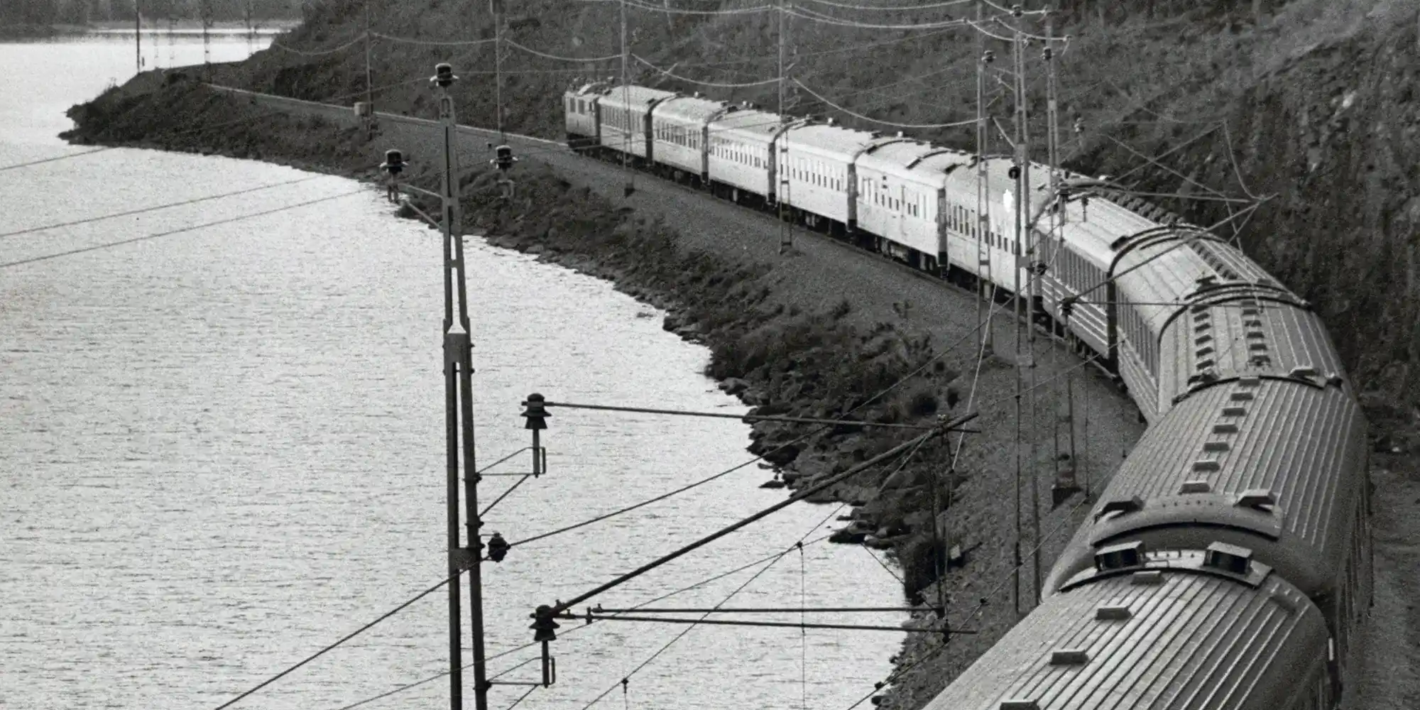 Lapplandspilen train going along river through forest